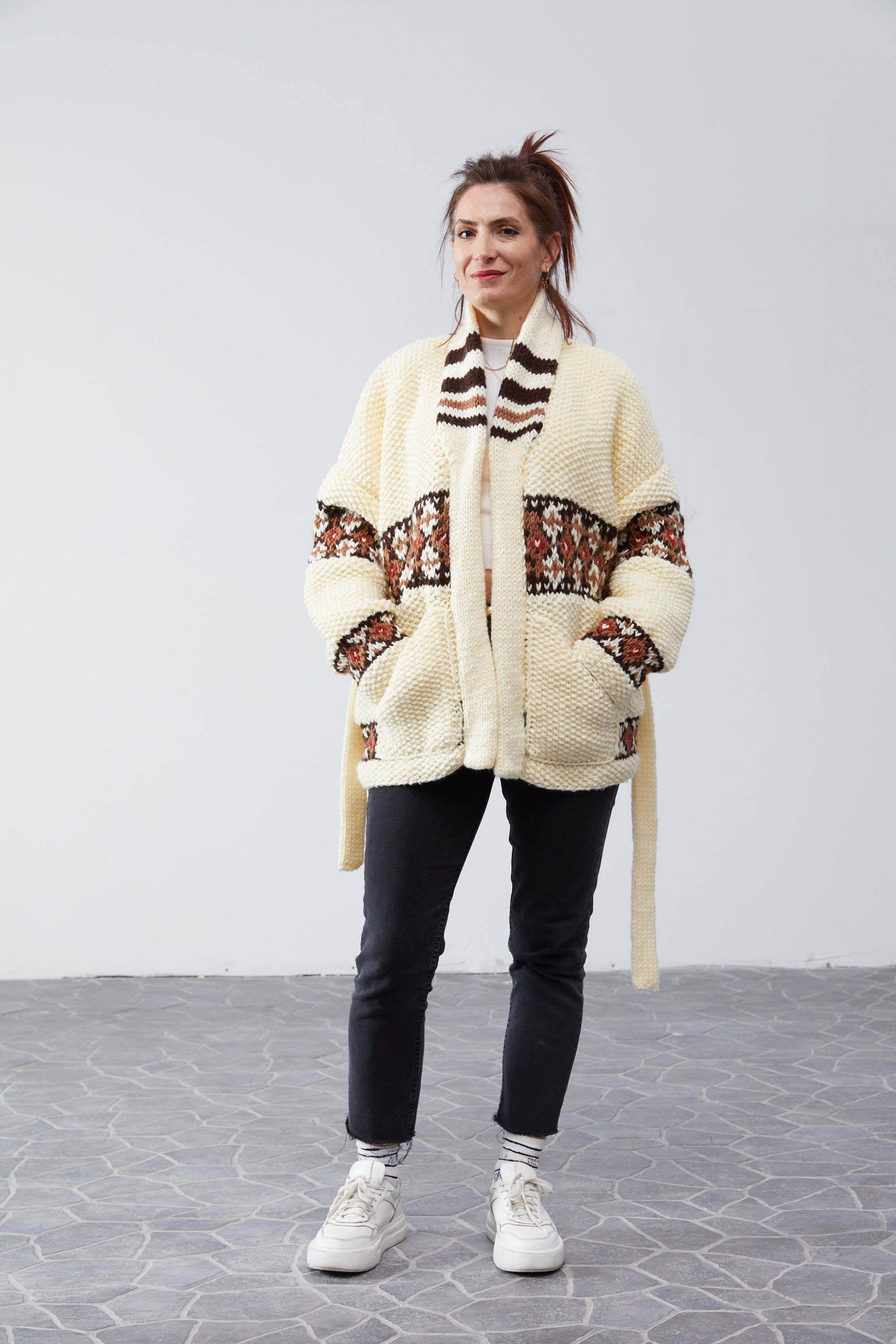 Marilyn Belted Cardigan in cream — hand-knit wool, model with hands in pockets