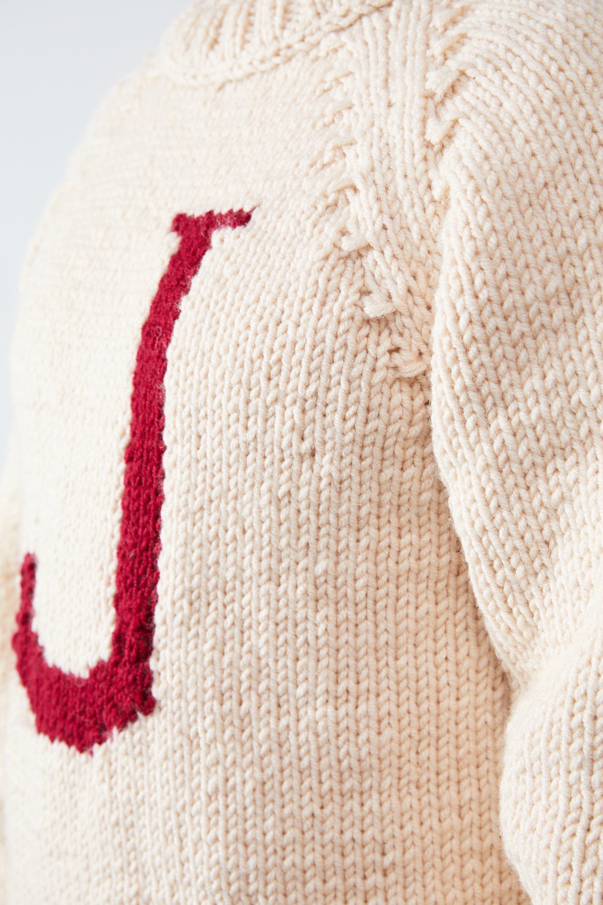 Close-up of red J letter knit detail on cream Monogram Weasley jumper