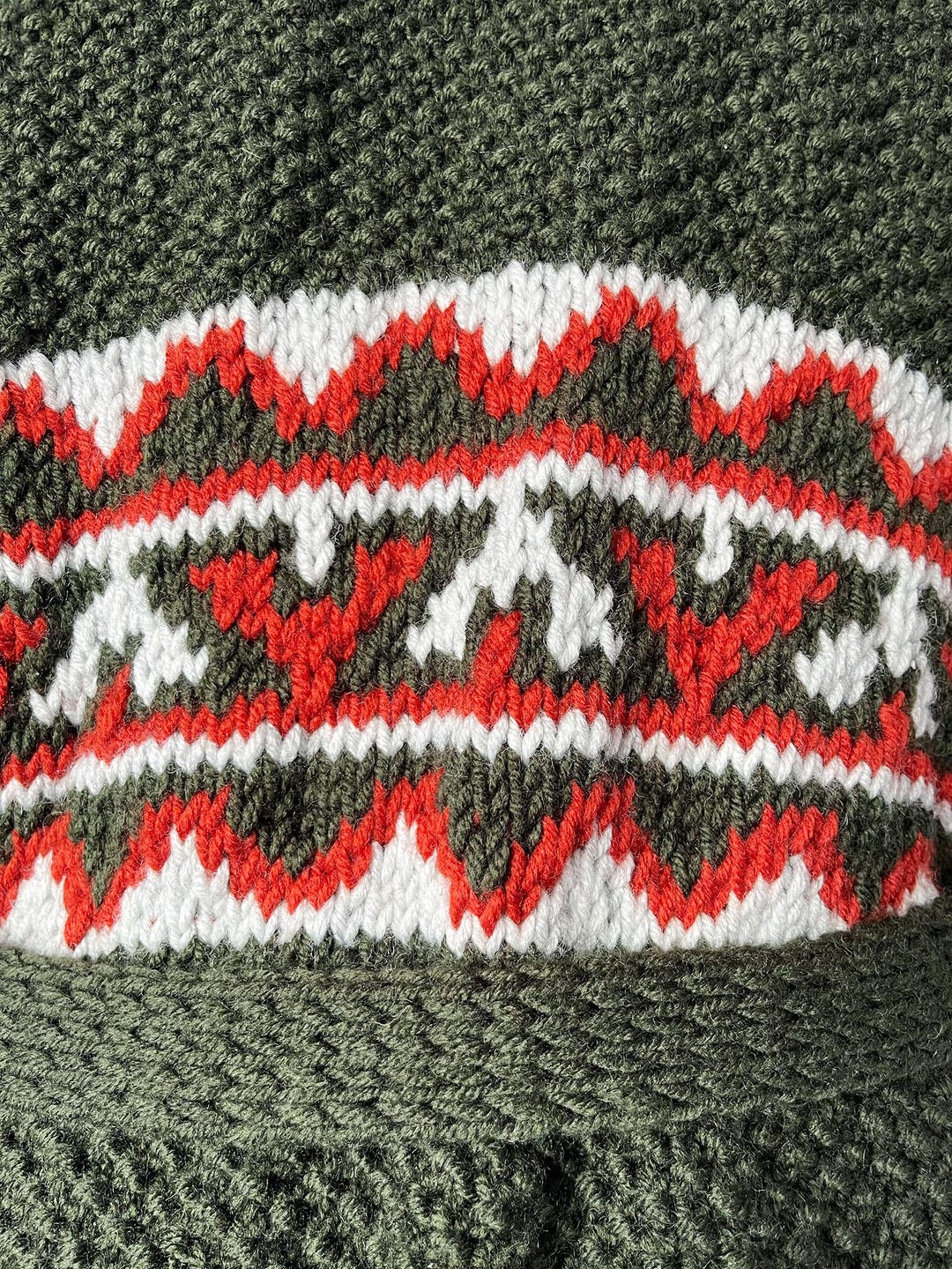 Close-up of green knit with white and red geometric band