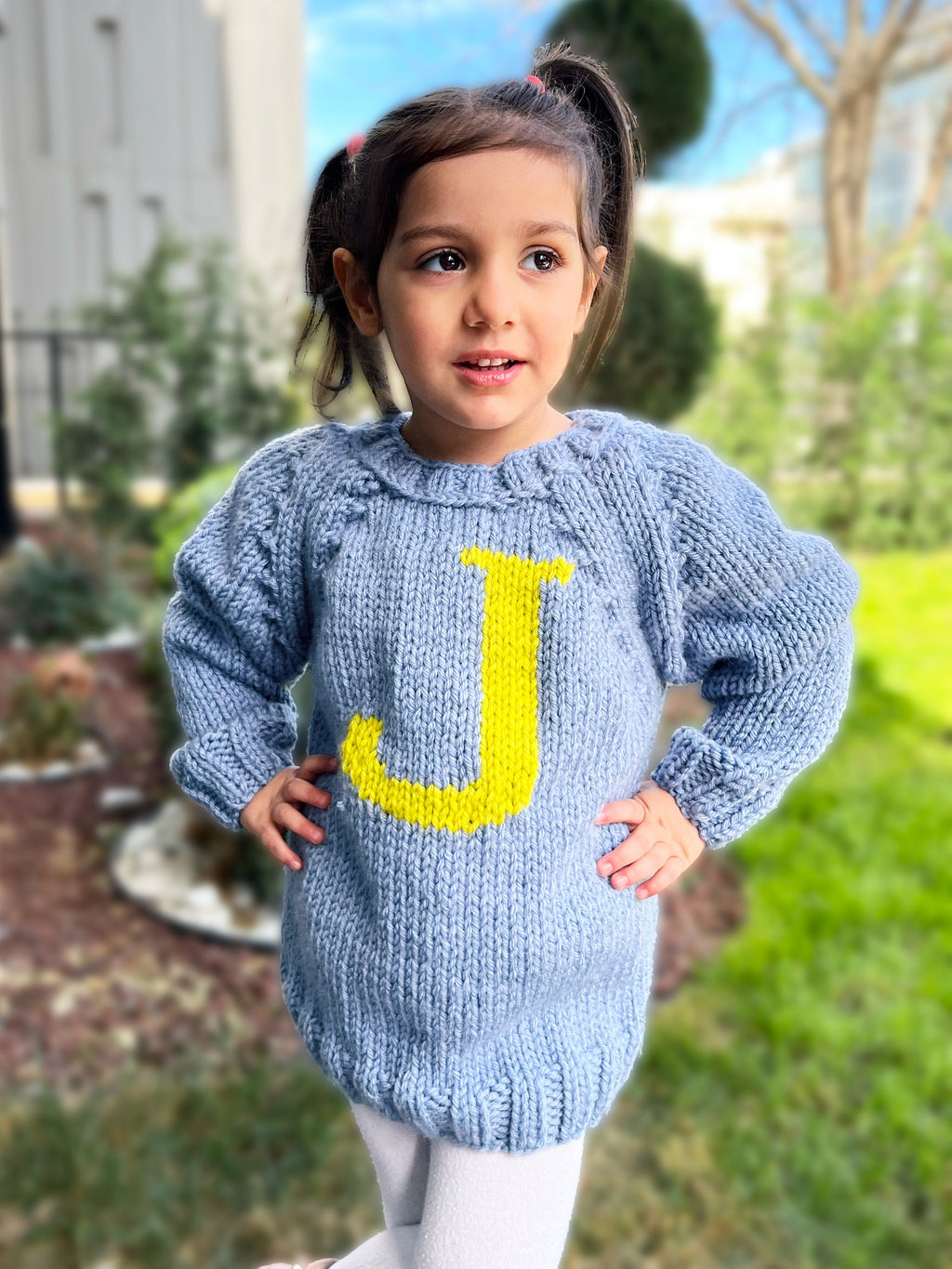 Girl in blue kids monogram sweater with yellow J letter — hand-knit