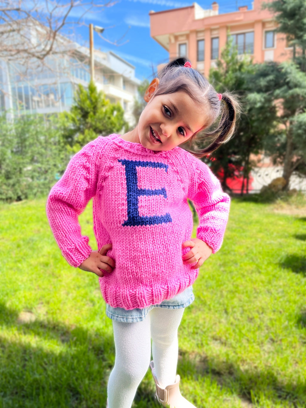 Girl in sugar pink kids monogram sweater with navy E letter — hand-knit