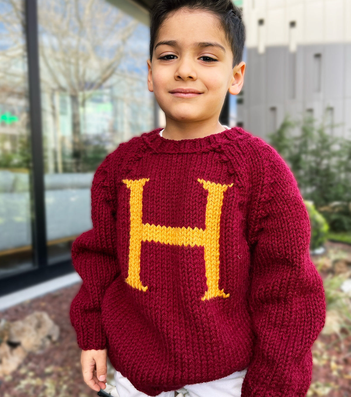 Burgundy kids monogram sweater with gold H initial, outdoor portrait