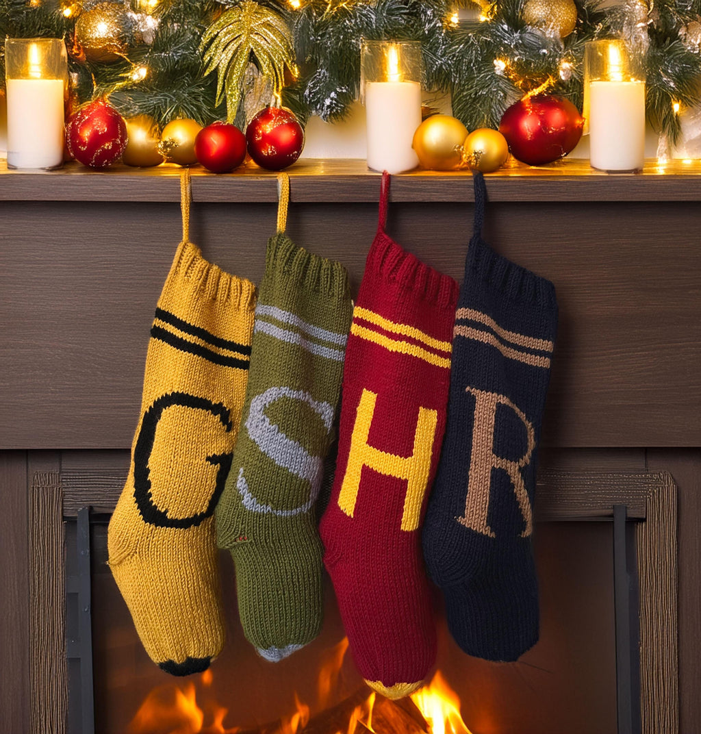 Four hand-knit monogram Christmas stockings — gold G, green S, burgundy H and navy R — hanging from a decorated mantel