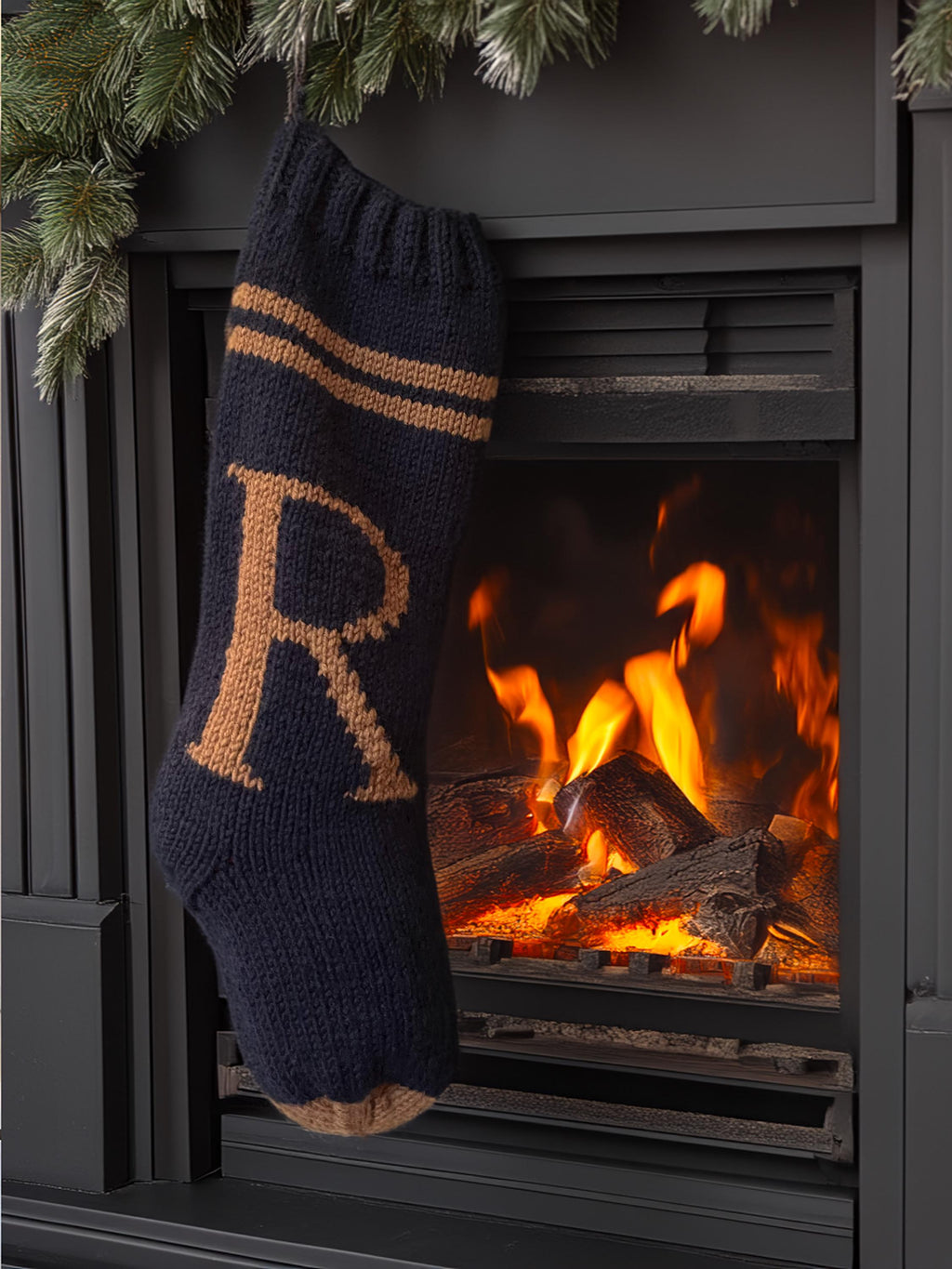 Navy hand-knit Christmas stocking with brown R letter, hanging from a dark mantel