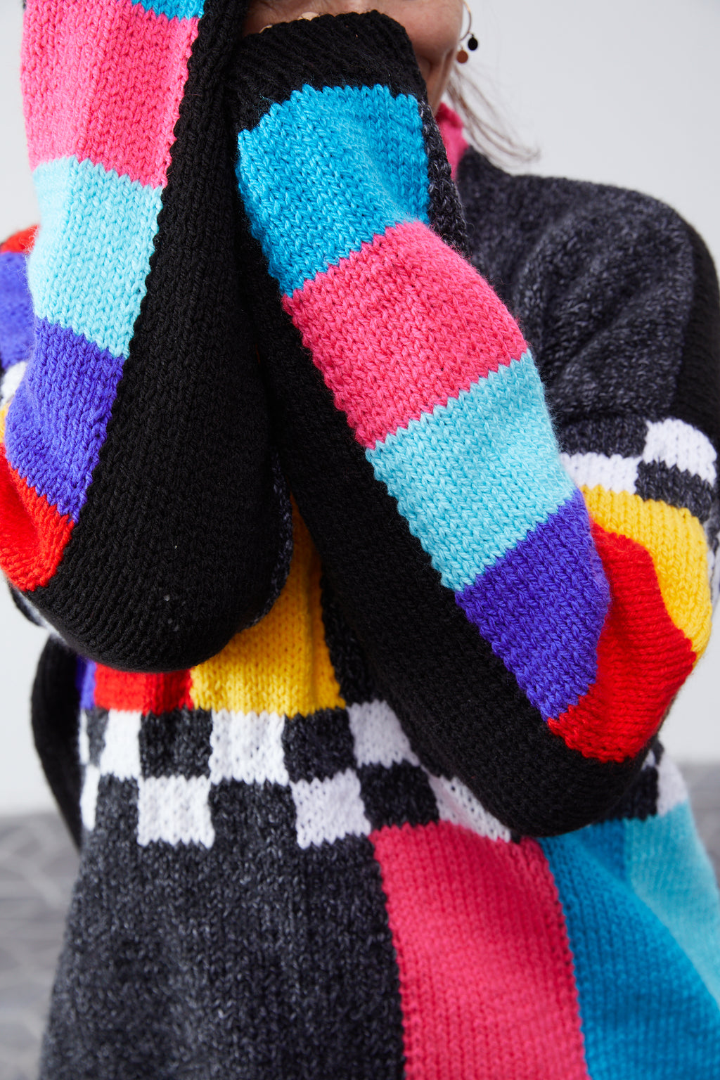 Hand-knit sweater sleeve detail with pink, blue, yellow and purple color bars